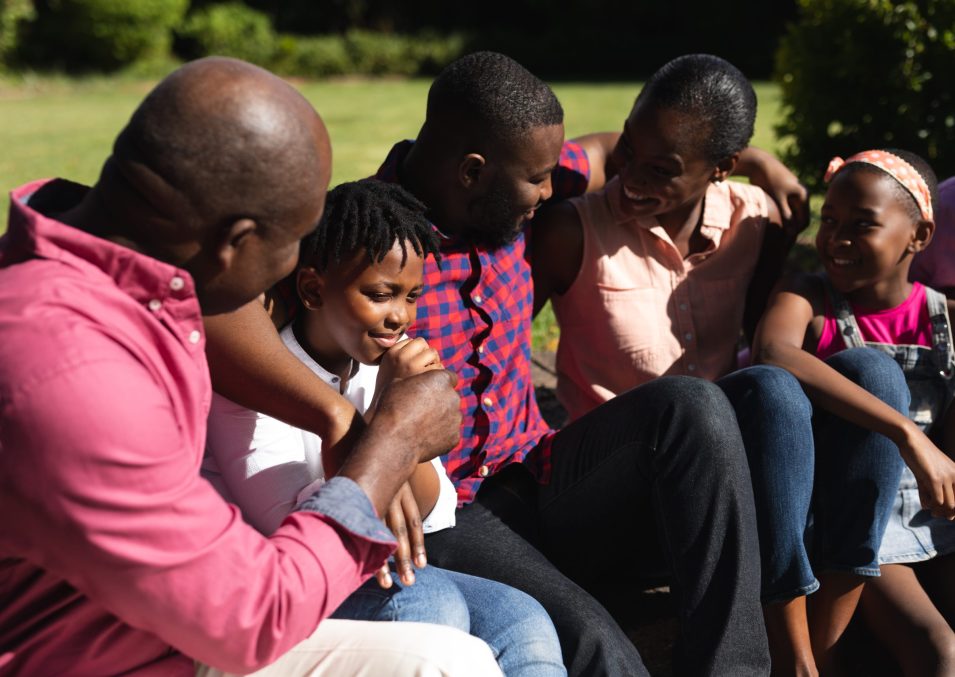 Smiling african american parents, grandfather, grandson and granddaughter embracing in garden. multi generation family spending time together at home.